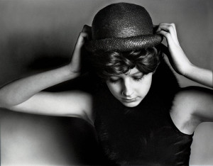 Portrait of a woman putting on a hat in black and white